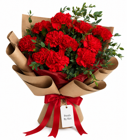 Red carnation bouquet wrapped in coffee brown paper with vibrant red satin ribbon by Petals By Riri