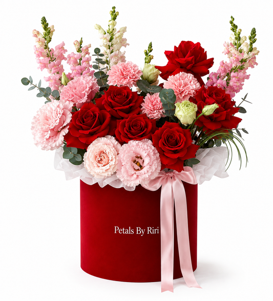 Red roses pink snapdragons carnations and lisianthus arrangement in a luxury red hatbox with pink ribbon by Petals By Riri